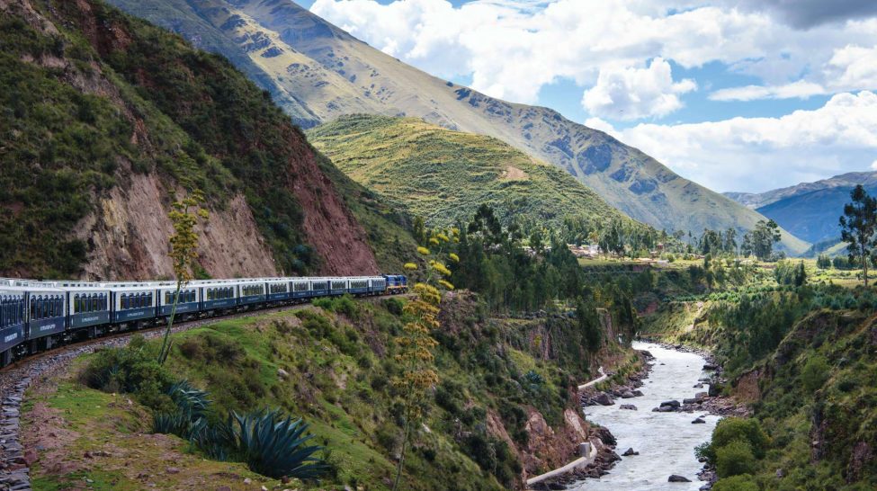 An old-fashioned steam train traversing a high mountain bridge.
